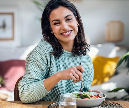 Woman in green sweater enjoying a salad and glass of waters
