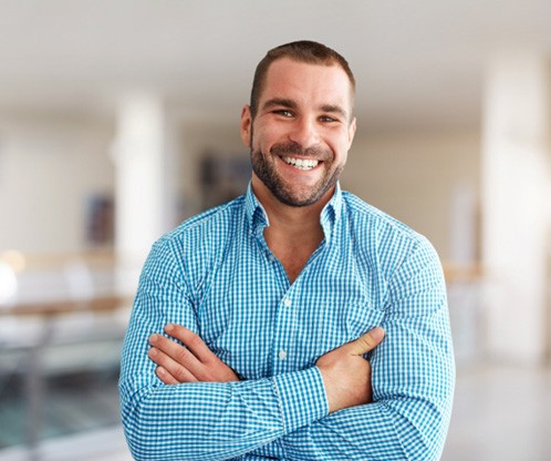 Smiling man standing with his arms folded