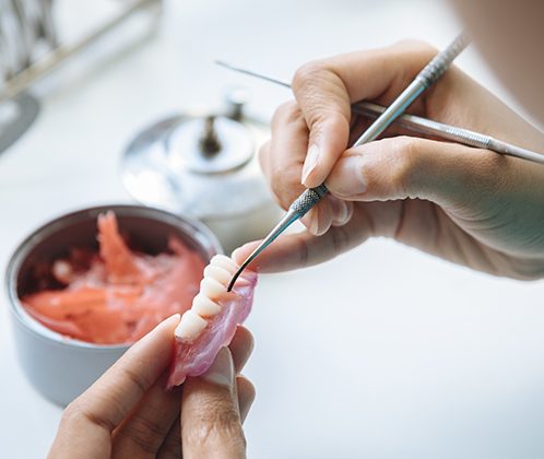 A technician making a denture’s base and artificial teeth