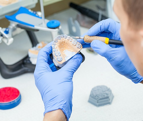 A dental technician working on a denture