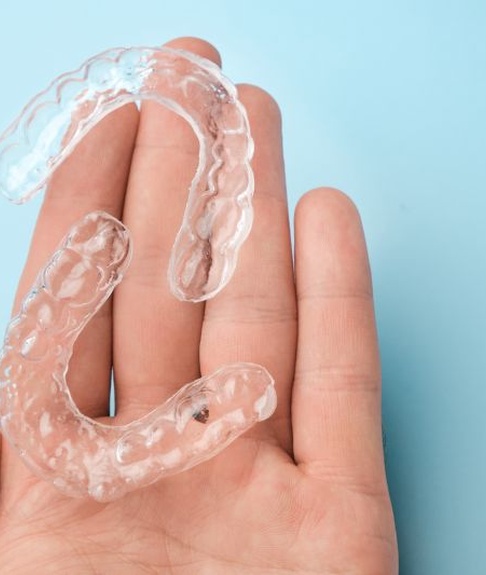 Two clear aligners resting on person’s hand