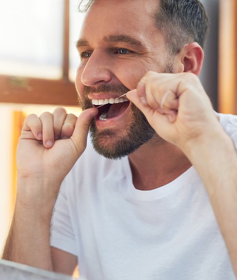 Patient in Lakewood flossing to prevent dental emergencies