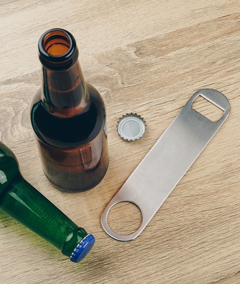 Patient in Lakewood using a bottle opener to avoid dental emergencies