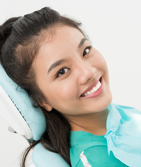 Woman smiling in dental chair after treatment for TMJ disorder in Lakewood, CO