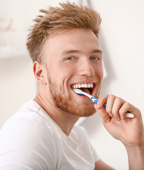 Man in white shirt brushing his teeth