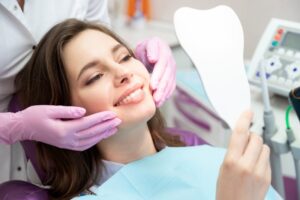 Woman smiling into mirror with beautiful smile after cosmetic dentistry