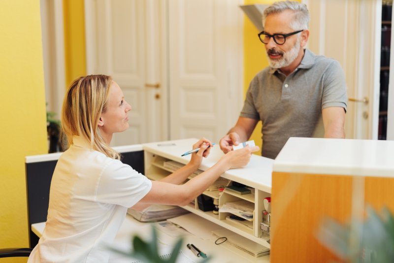 An older man paying for affordable cosmetic dentistry