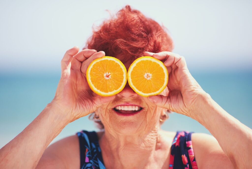 A woman holding orange slices over her eyes.